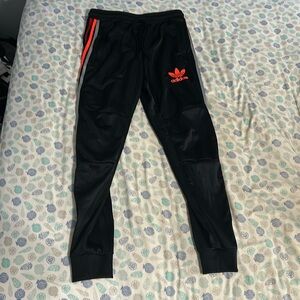 Adidas black track pants with red and orange stripes